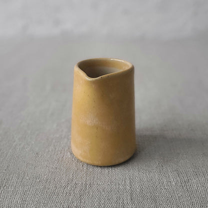 Cream yellow mini jug in beige background