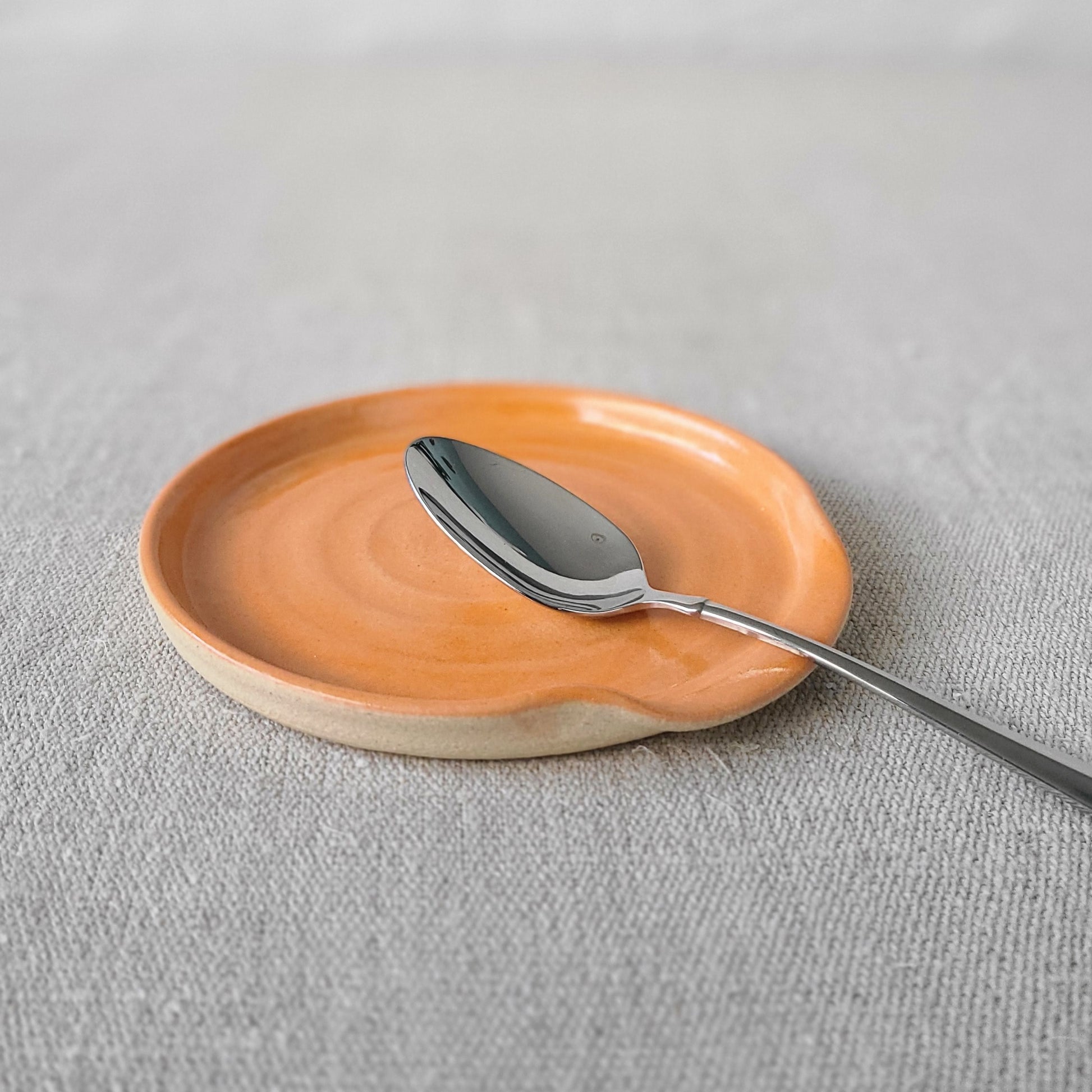 Orange spoon rest with silver teaspoon